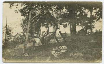 A picture of Devil Anse Hatfield (left far back) Betty Caldwell, Madie, and unidentified individuals sitting in a swing set on a rock cliff.