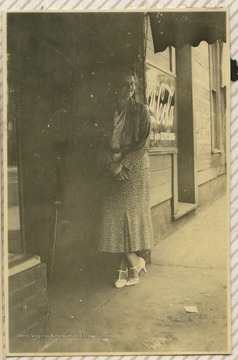 Photograph of Ruby Gibson standing at a Coca-Cola storefront.